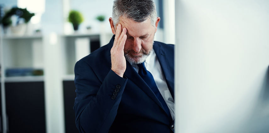 Shot of a mature businessman experiencing a headache while working at his desk in a modern office